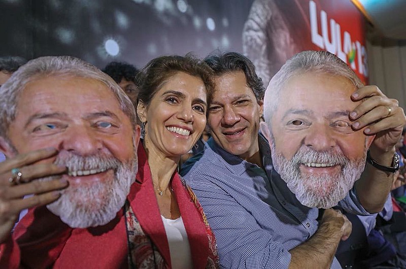Ana Estela e Fernando Haddad seguram máscaras de Lula durante a campanha