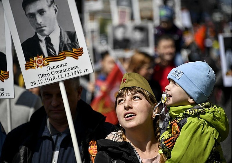Mulher segura cartaz que traz foto de um herói de guerra na Praça Vermelha, em Moscou