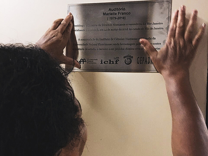 Ana Lúcia Oliveira coloca a placa com a nomeação de Marielle ao auditório do Instituto de Ciências Humanas e Filosofia (ICHF) da UFF