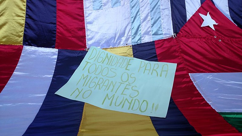 Cartaz na Marcha dos Imigrantes de 2016 pede dignidade para os migrantes no mundo todo