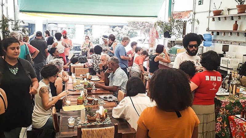 Dezenas de pessoas desfrutam de produtos da reforma agrária durante almoço no Armazém do Campo