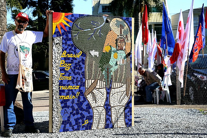 Vilmar ao lado de quadro feito em homenagem à Lula na luta contra a fome