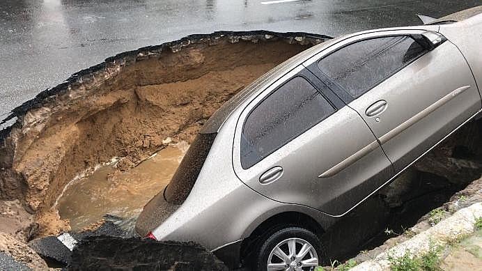 Carro engolido por buraco provocado pelas chuvas, no Bairro dos Estados, em João Pessoa (PB)