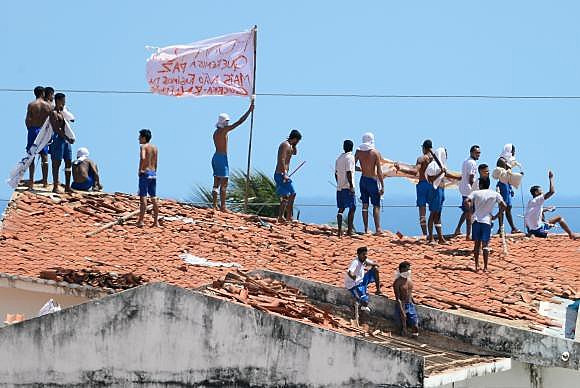 Alcaçuz: confronto entre tropas de choque da Polícia Militar e detentos; operários constroem muro de contâineres