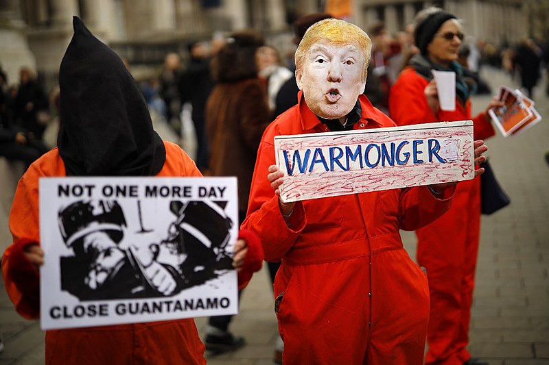 Manifestante disfarçado de Trump ergue cartaz com a palavra "warmonger" ("promotor da guerra"), durante protesto em Londres, Reino Unido