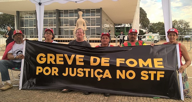 Militantes que estão em greve de fome desde a última terça (31) seguram faixa em frente à sede do STF em Brasília