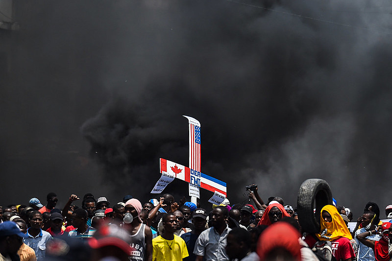 Manifestantes carregam imagens cruzadas de bandeiras do Canadá, dos EUA e da França durante uma marcha de protesto contra o governo