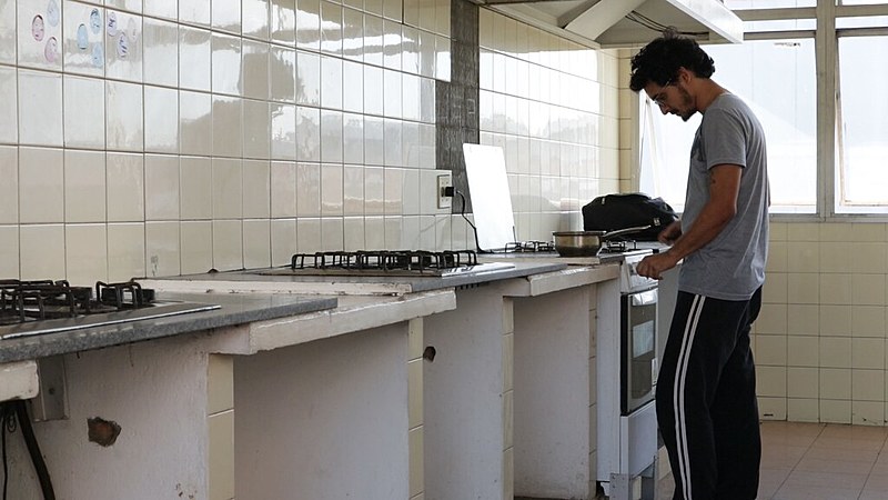 O morador Wagner Rodolfo esquenta água em uma das cozinhas coletivas do bloco F