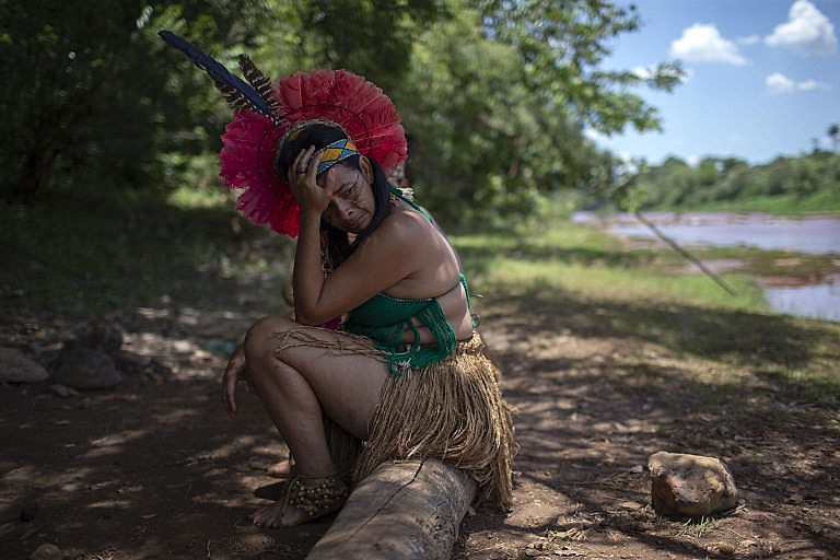 Indígena da comunidade Pataxo Ha-ha-hae chora ao lado do rio Paraopeba