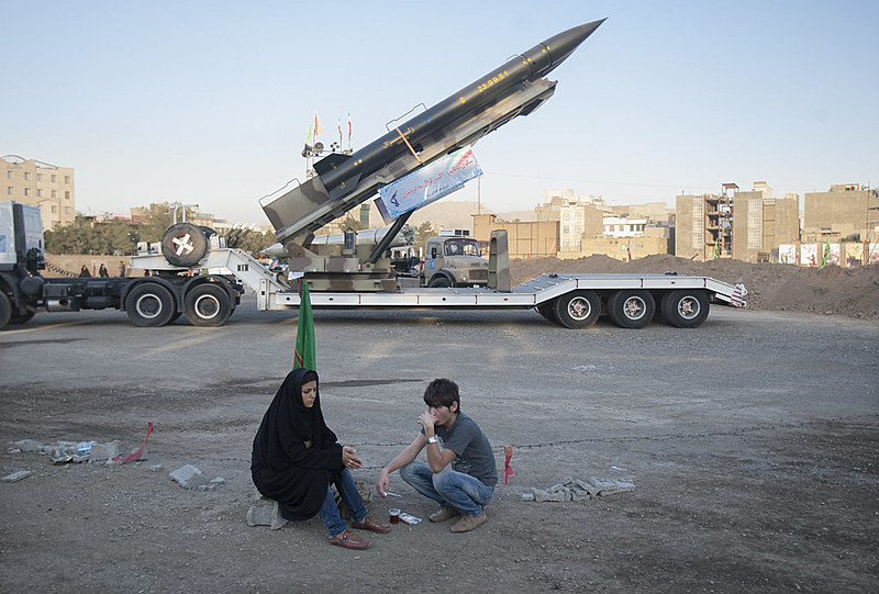 Casal iraniano descansa em frente ao míssil Zelzal enquanto visita uma exposição de guerra para marcar o aniversário da guerra Irã-Iraque