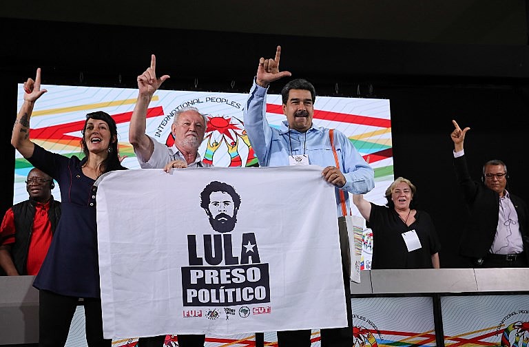 Maduro levanta uma bandeira com as inscrições "Lula Preso Político" junto ao dirigente do MST, João Pedro Stedile, durante ato na AIP