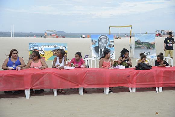 Mesa coberta por uma toalha vermelha simbolizando o sangue das vítimas foi estendida na areia