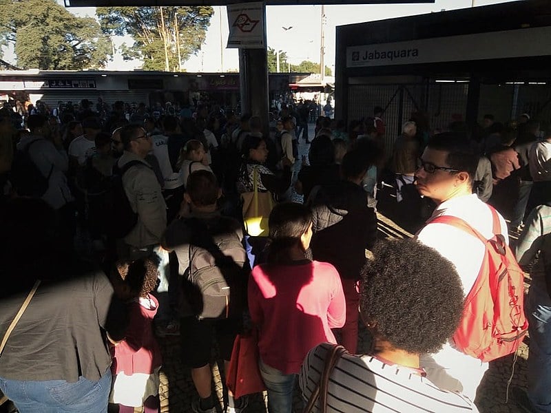 Trabalhadoras e trabalhadores aguardam em frente aos portões por informações sobre o funcionamento do transporte