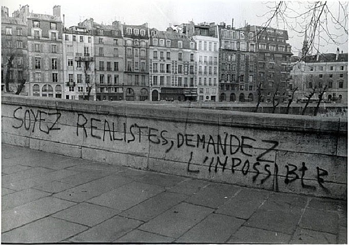 Muro em Paris traz a mensagem “sejamos realistas, exijamos o impossível”
