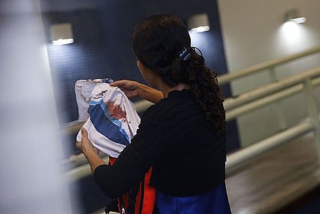 Bruna, mãe do adolescente Marcos Vinicius da Silva, segura camisa da escola que o estudante usava