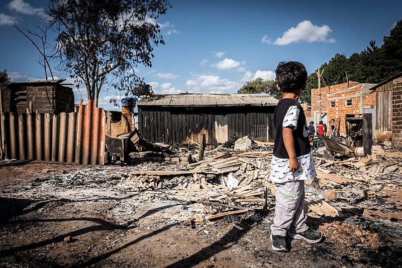 Garoto observa os escombros de ocupação incendiada