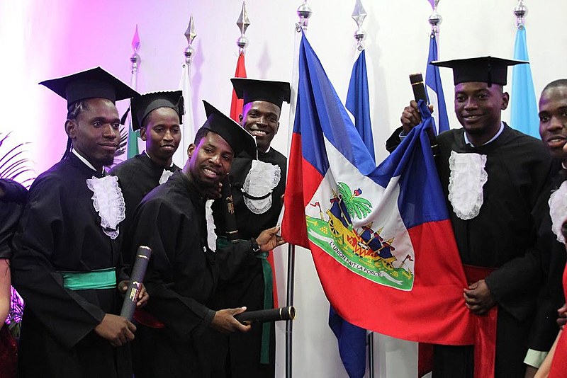 Formandos comemoram ao lado da bandeira do Haiti