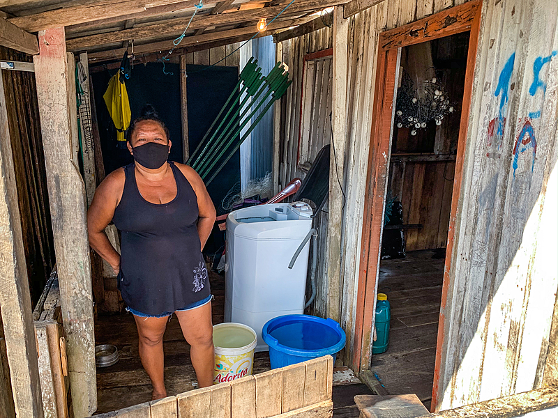 Dona Angélica, de 44 anos, na frente da sua casa. Ela usa diversos recipientes para armazenar água limpa.