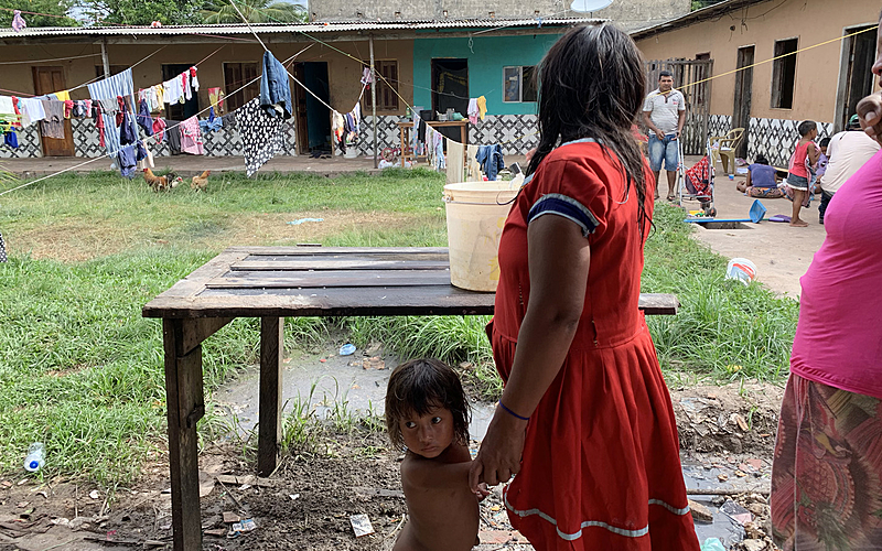 Mãe e criança Warao em frente a um jirau – usado para lavar louça.