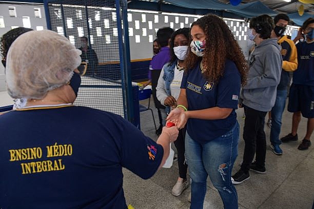 Aluna higieniza as mãos ao entrar na escola Milton da Silva Rodrigues em São Paulo, nesta terça-feira (3), no primeiro dia de retorno às aulas de alunos do ensino médio no estado de São Paulo