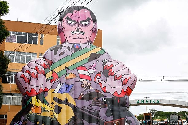 Manifestantes erguem um boneco inflável do presidente Jair Bolsonaro em frente à sede da Anvisa neste domingo (17), dia em que a agência decide sobre uso emergencial de vacinas contra covid