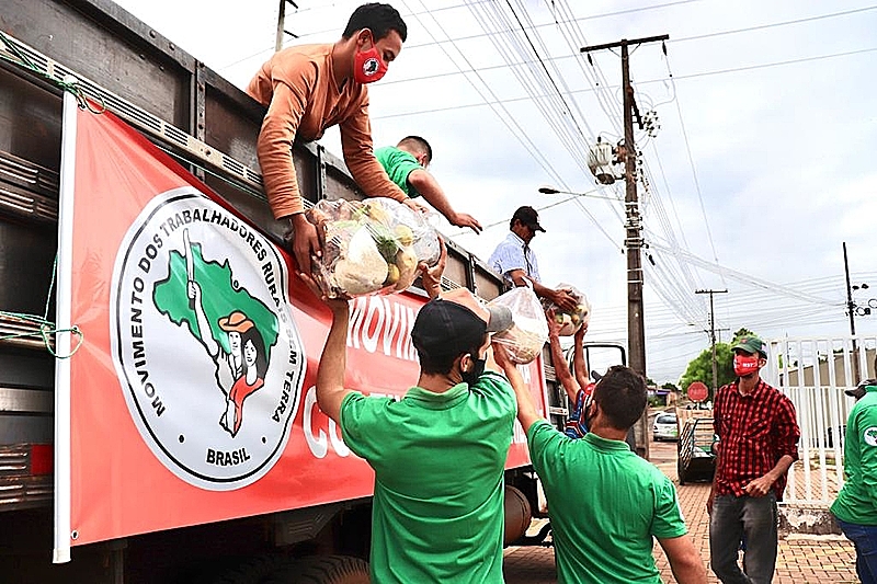 Famílias descarregam um caminhão com alimentos
