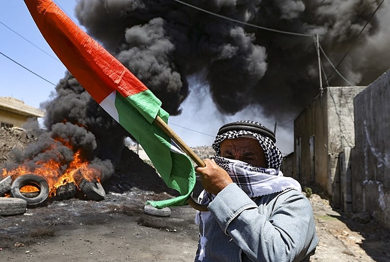 Homem empunha a bandeira Palestina durante ataque das forças de Israel à vila de Kfar Qaddum, nesta sexta-feira (1). O ataque aconteceu após protesto de palestino contra a expropriação de suas terras