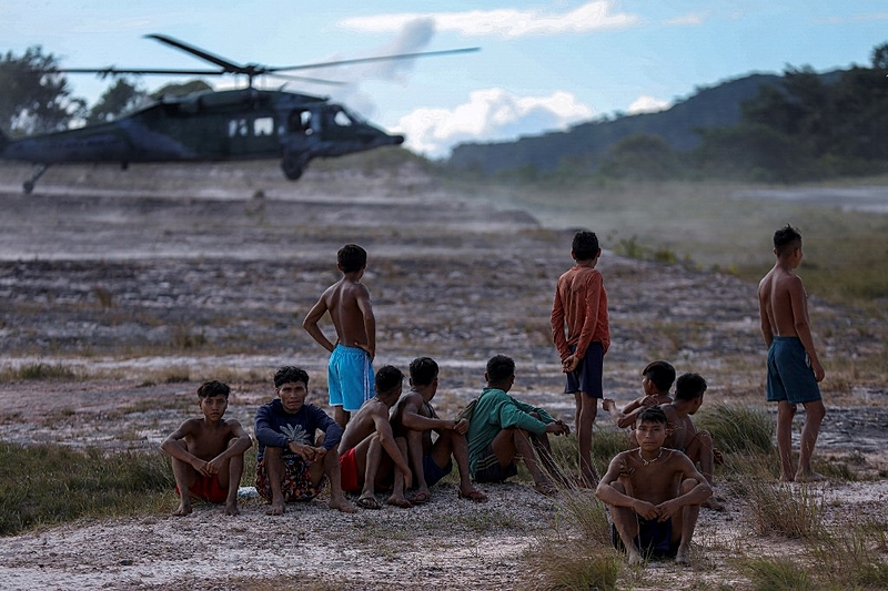 Indígenas do povo Yanomami observam helicóptero da Força Aérea que atua no resgate de casos de malária e desnutrição em Alto Alegre (Roraima)