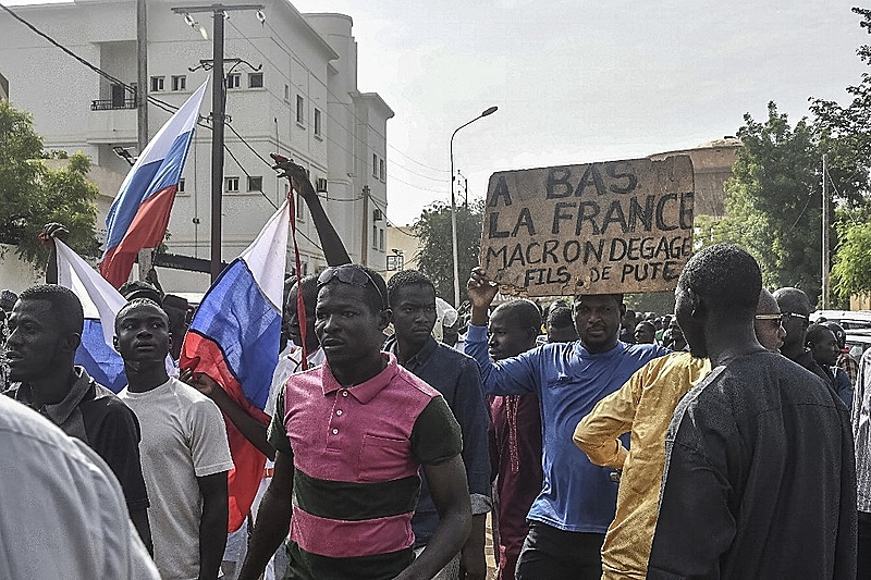 Apoiadores agitam bandeiras russas e um cartaz com um slogan anti-França enquanto se reúnem em apoio à junta militar do Níger
