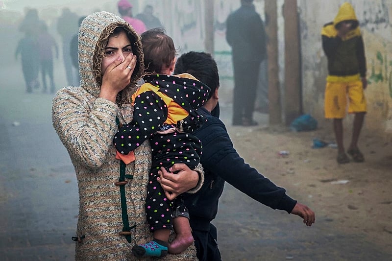 Mulher segura criança após ataque israelense em Rafah, no sul da Faixa de Gaza, em 23 de novembro de 2023