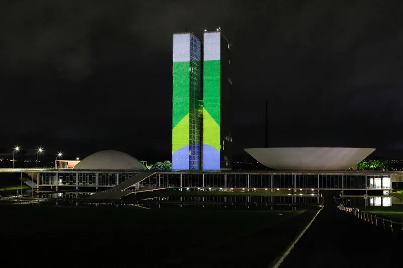 Projeção da bandeira brasileira no Congresso Nacional reforça valores da democracia no marco de um ano dos ataques golpistas de 8 de janeiro.