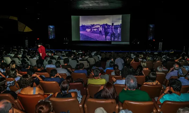 Pessoas em uma sala de cinema assistem a um filme