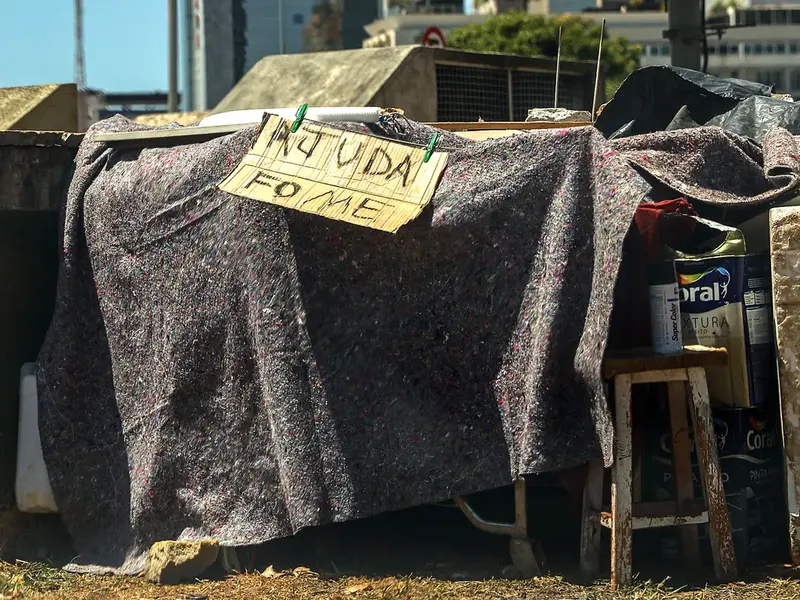 Acampamento na rua com placa que diz 'Ajuda, fome'