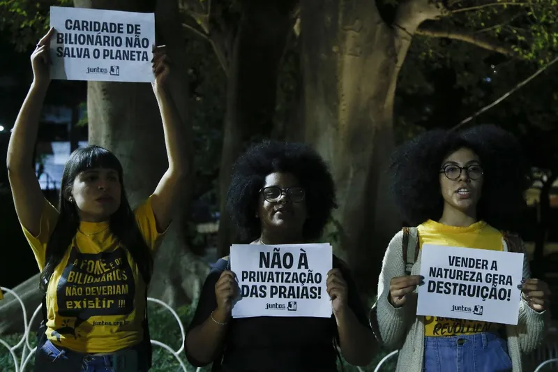 Manifestantes seguram faixas contra a privatização das praias na entrada do leilão beneficente do Instituto Neymar, em São Paulo, em 3 de junho de 2024.