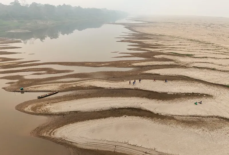 Pessoas carregam água potável ao longo de um banco de areia do Rio Madeira quase seco, na Comunidade de Paraizinho, em Humaitá (AM)
