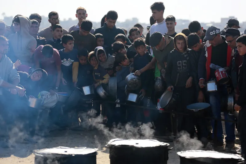 Palestinos aguardam por uma porção de comida em um centro de distribuição em Khan Yunis, no sul da Faixa de Gaza, em 17 de dezembro de 2024