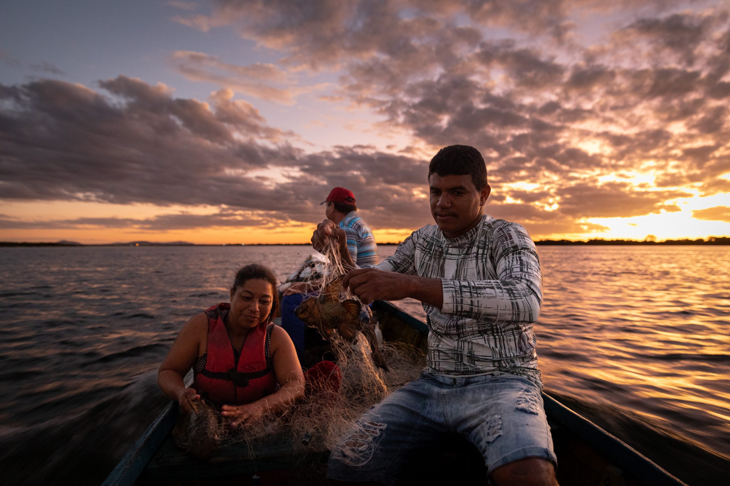 família de pescadores em barco na água, ao por do sol