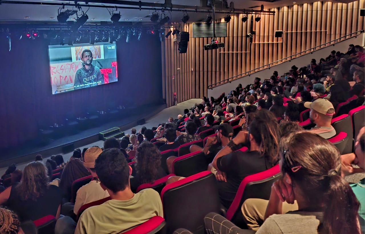 auditório cheio com tela exibindo a série documental território em fluxo