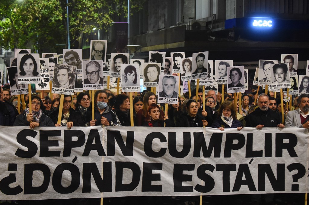Pessoas seguram retratos dos desaparecidos durante a última ditadura no Uruguai enquanto participam da Marcha del Silencio (Marcha do Silêncio) em Montevidéu, em 20 de maio de 2025