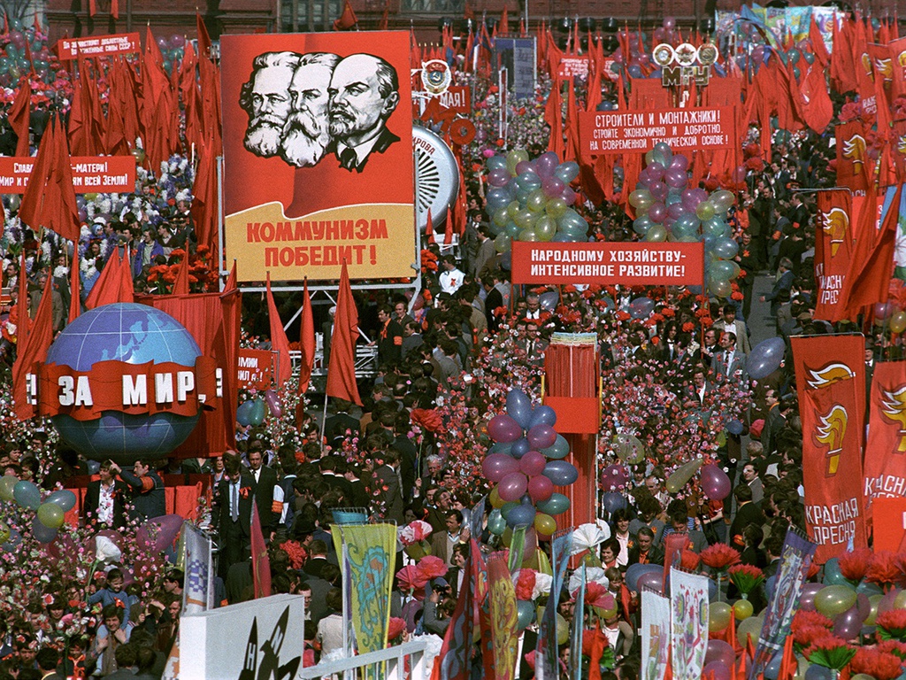 Celebração do 1º de Maio de 1982, na Praça Vermelha, em Moscou. Em destaque, cartaz com o retrato de Marx, Engels e Lenin, com a frase "Comunismo vencerá!"