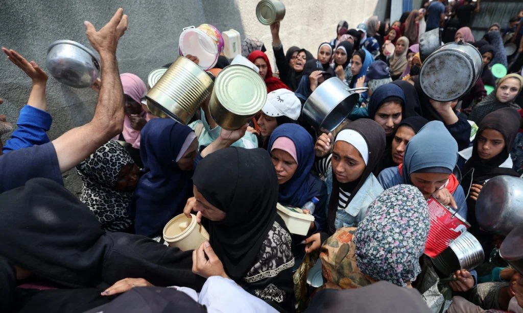 Mulheres palestinas aguardam a distribuição de refeições quentes em Nuseirat, região central da Faixa de Gaza, em 4 de junho de 2025