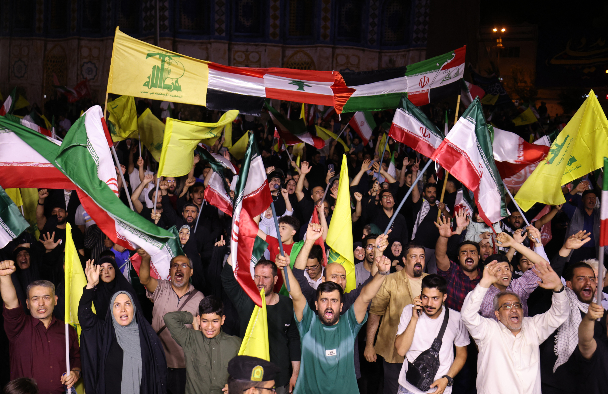 Iranianos agitam bandeiras e celebram, nas ruas da capital Teerã, nesta sexta-feira (13), um ataque com míssil que atingiu Tel Aviv, capital israelense, em resposta ao bombardeio desta quinta (12)