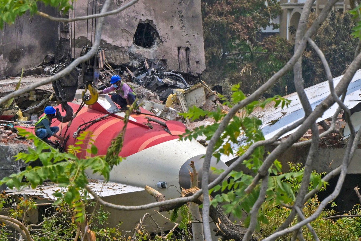 Trabalhadores removendo a cauda do avião dos destroços após a queda do voo 171 da Air India em 12 de junho, em uma área residencial perto do aeroporto de Ahmedabad, em 14 de junho de 2025