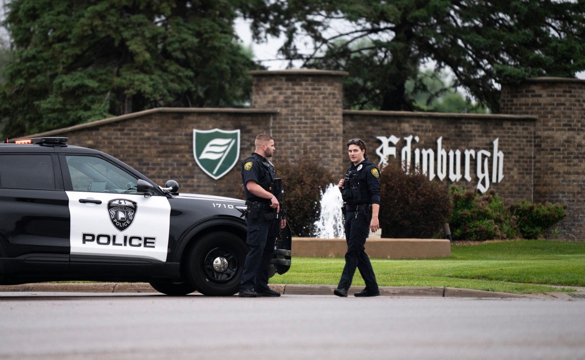 Policiais conversam enquanto guardam a entrada de um bairro em 14 de junho de 2025 no Brooklyn Park, Minnesota