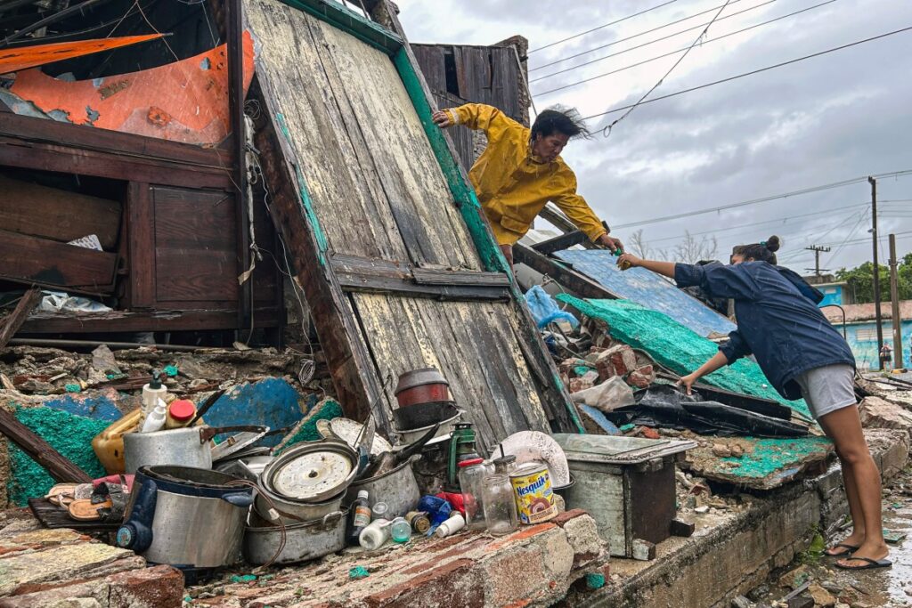 Uma família resgata pertences dos escombros de sua casa após o desabamento causado pelo furacão Melissa em Santiago de Cuba, Cuba, em 29 de outubro de 2025. Foto: Luis Alejandro Pirez / AFP

