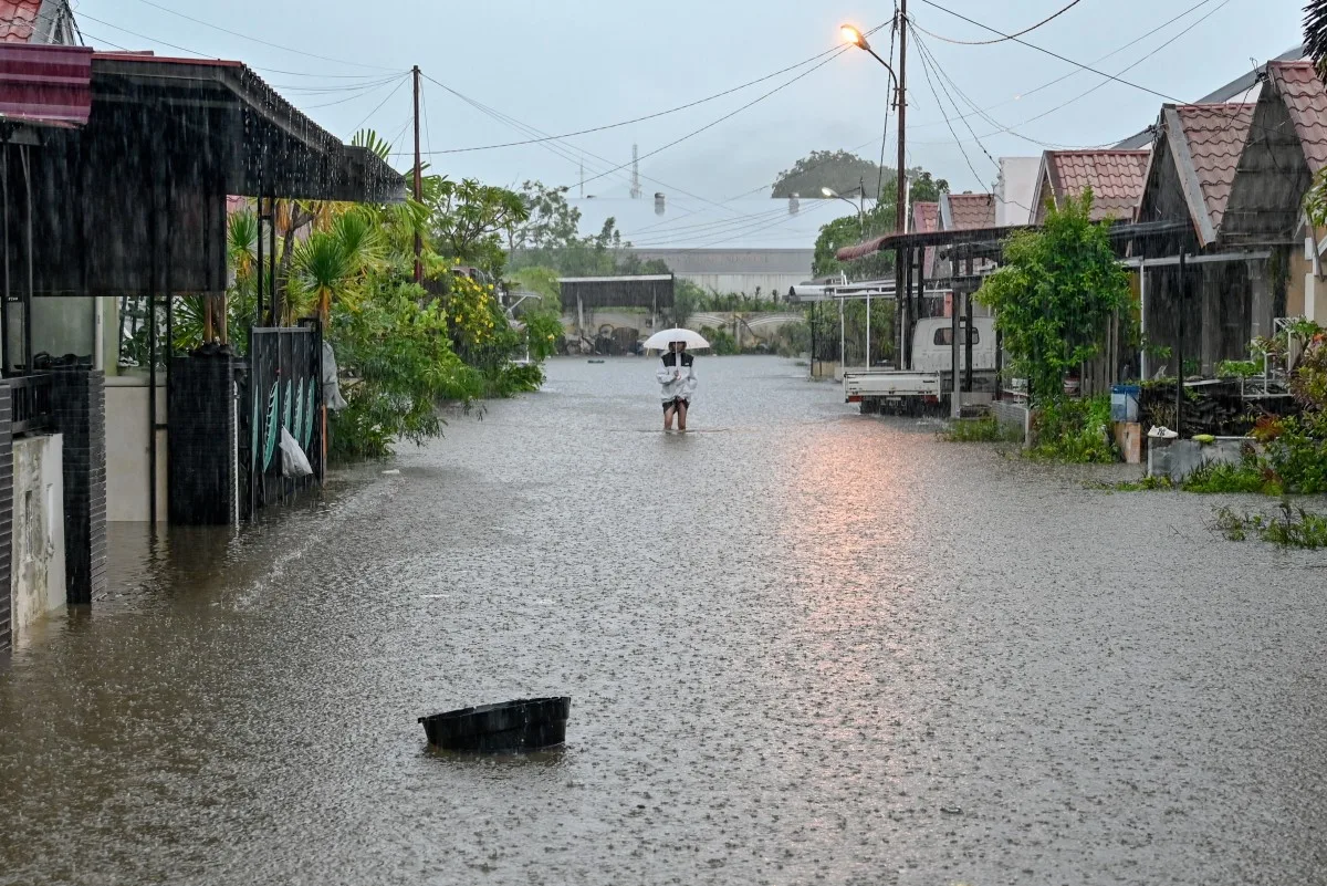 Um homem caminha pela água da enchente em uma rua alagada após fortes chuvas em uma área residencial de Darul Imarah, nos arredores de Banda Aceh, em 27 de novembro de 2025