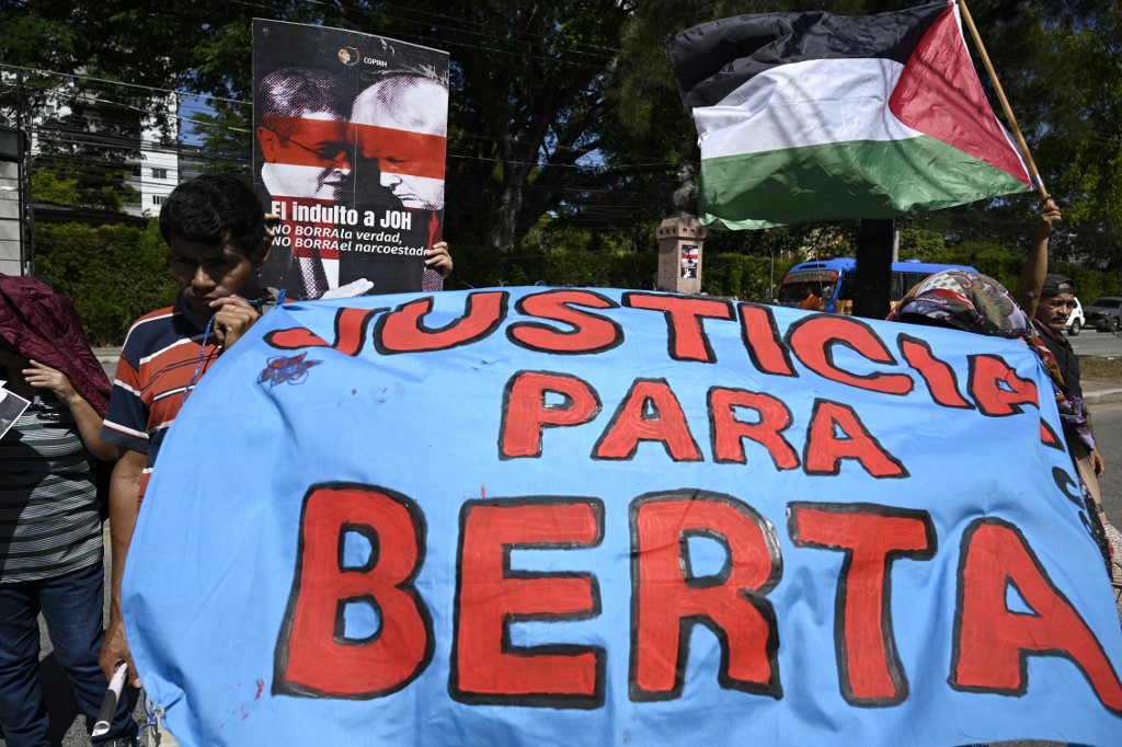 Uma mulher segura um cartaz onde se lê: “O perdão para Juan Orlando Hernández (JOH) não apaga a verdade, não apaga o narco-Estado”,