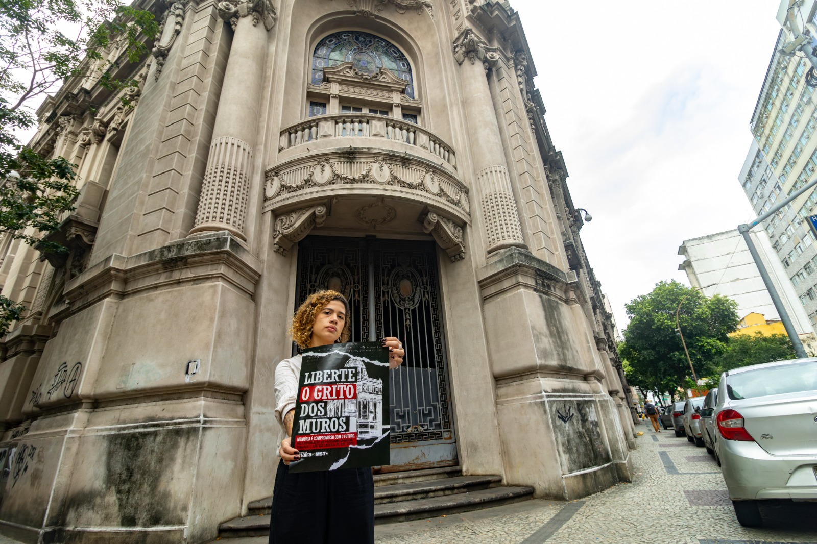Vereadora Maíra do MST (PT) segura cartaz da campanha "Liberte o grito dos muros" em frente ao prédio do Dops