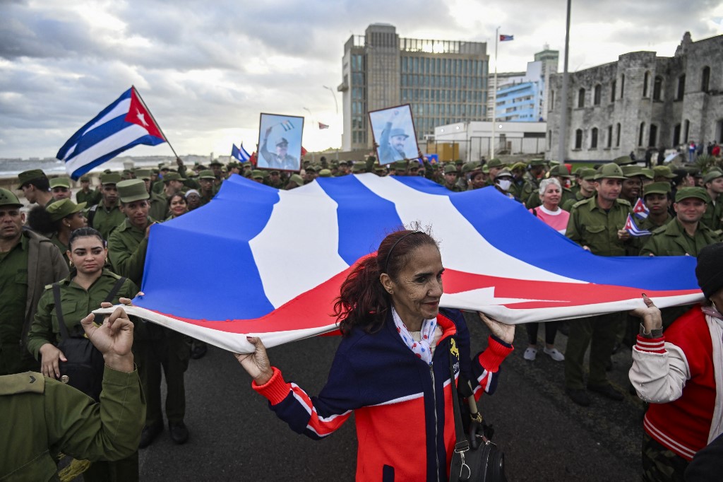 Manifestantes seguram uma enorme bandeira cubana durante um protesto “Anti‑Imperialista” em frente à Embaixada dos EUA, contra a incursão dos EUA na Venezuela, onde 32 soldados cubanos perderam a vida, em Havana, em 16 de janeiro de 2026.