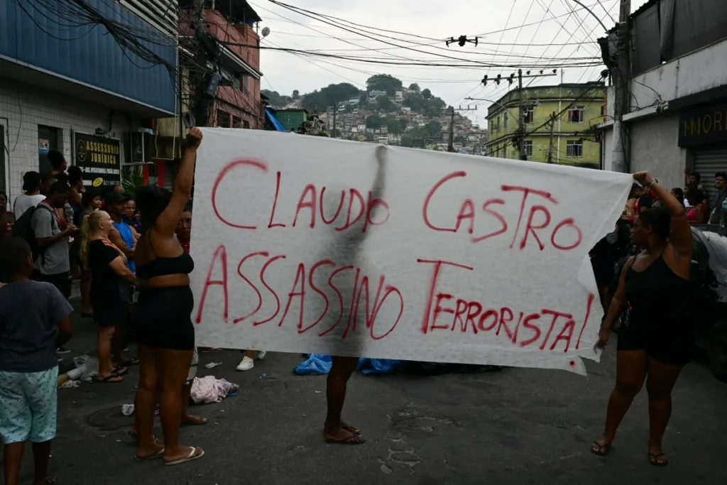 Pessoas protestam enquanto moradores enfileiram corpos na Praça São Lucas, na favela Vila Cruzeiro, Complexo da Penha, Rio de Janeiro, Brasil, em 29 de outubro de 2025, após a Operação Contenção. Pablo Porciuncula / AFP.
